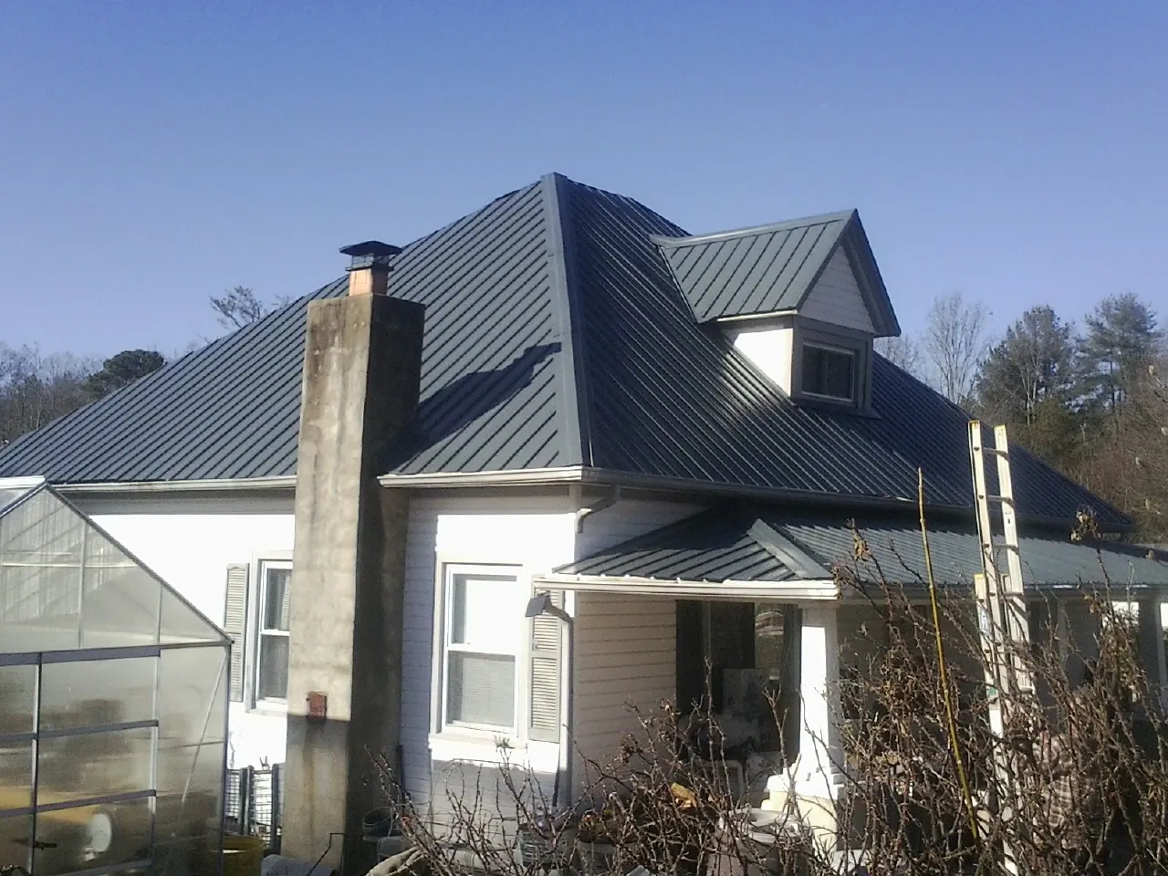 Dark blue standing seam metal roof on a white farmhouse with dormer — Slate & Tile Roof Repair by Roofing Brothers in West Springfield