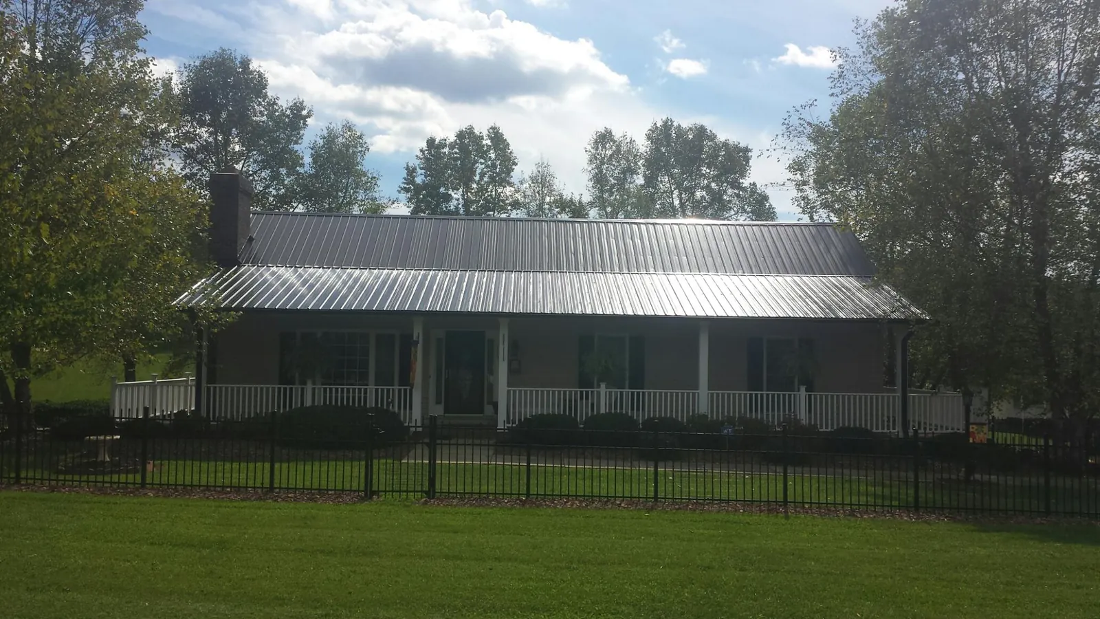 Gray metal roof on a brick ranch with a full width front porch — Gutter Guard Installation work by our crew in West Springfield