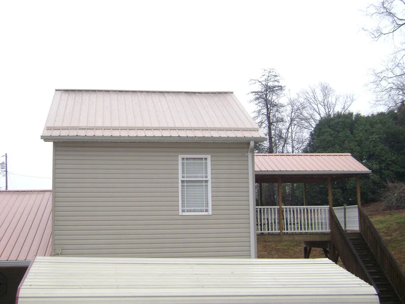 Tan metal roofs on a two story addition and attached porch, from a Roof Replacement job in West Springfield
